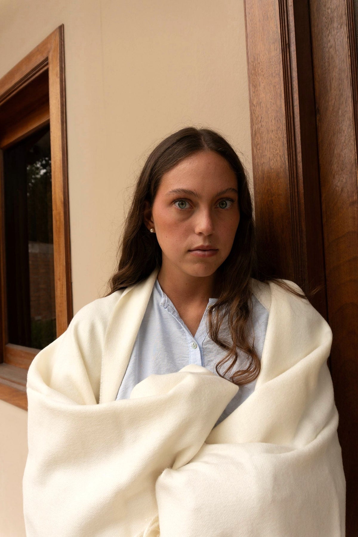A woman wrapped in the Natural throw in a doorway