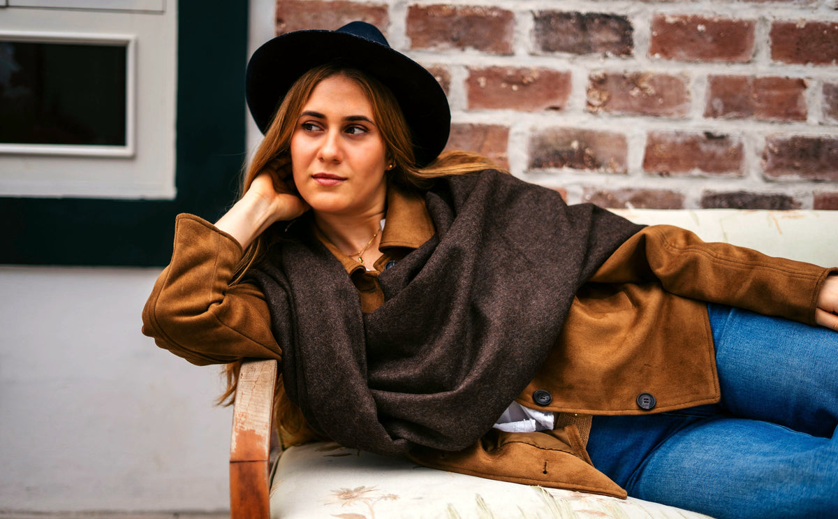 Andean brown baby alpaca throw over a jacket, seated on a hacienda bench
