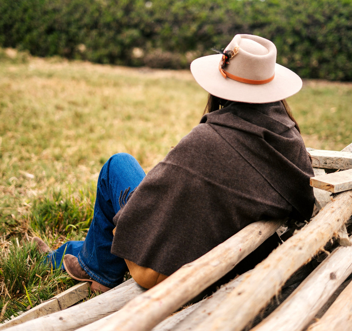 Andean brown baby alpaca throw over the shoulders, wide-brim hat, seen from behind