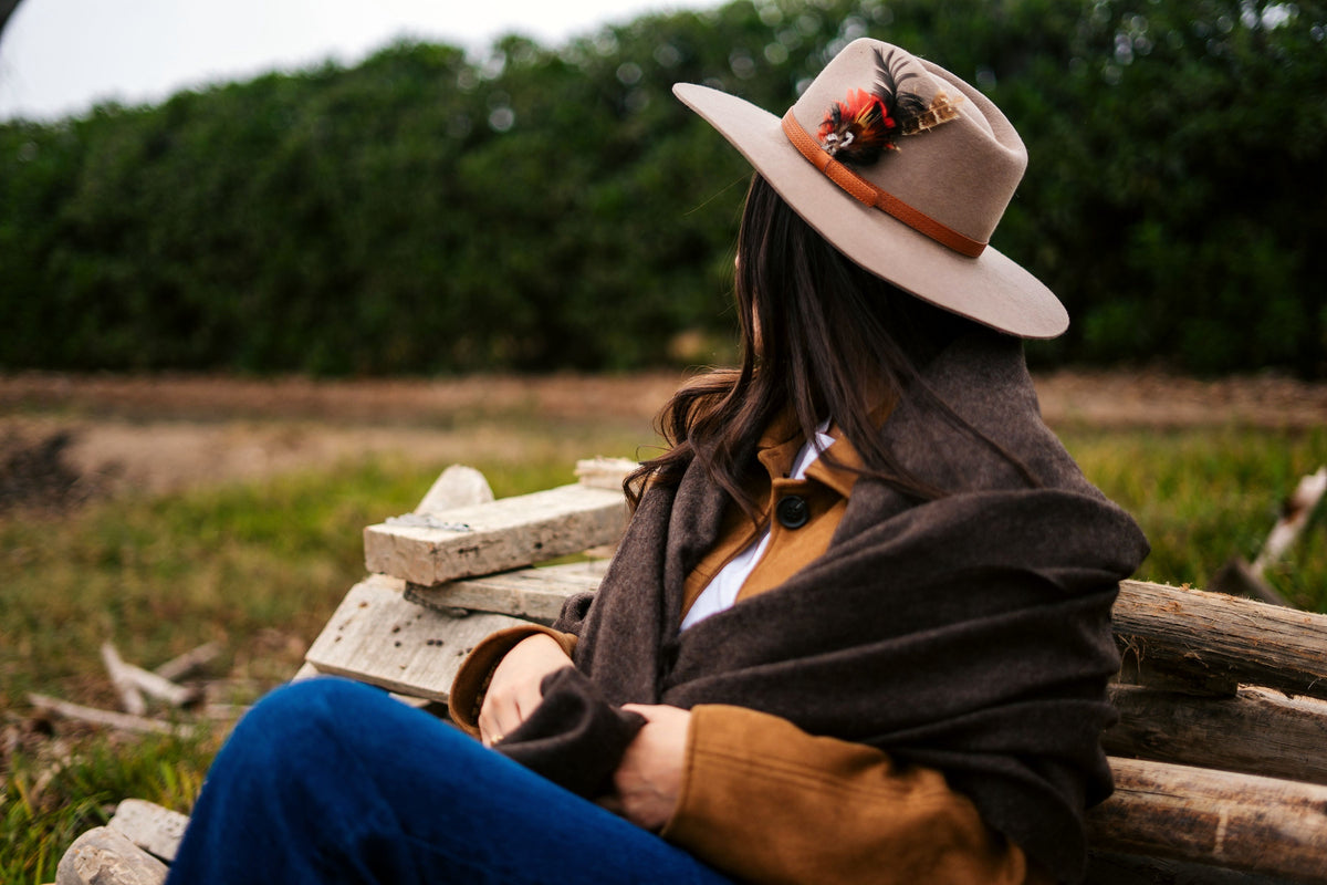 Model seated on a log wrapped in the Vicuña brown throw